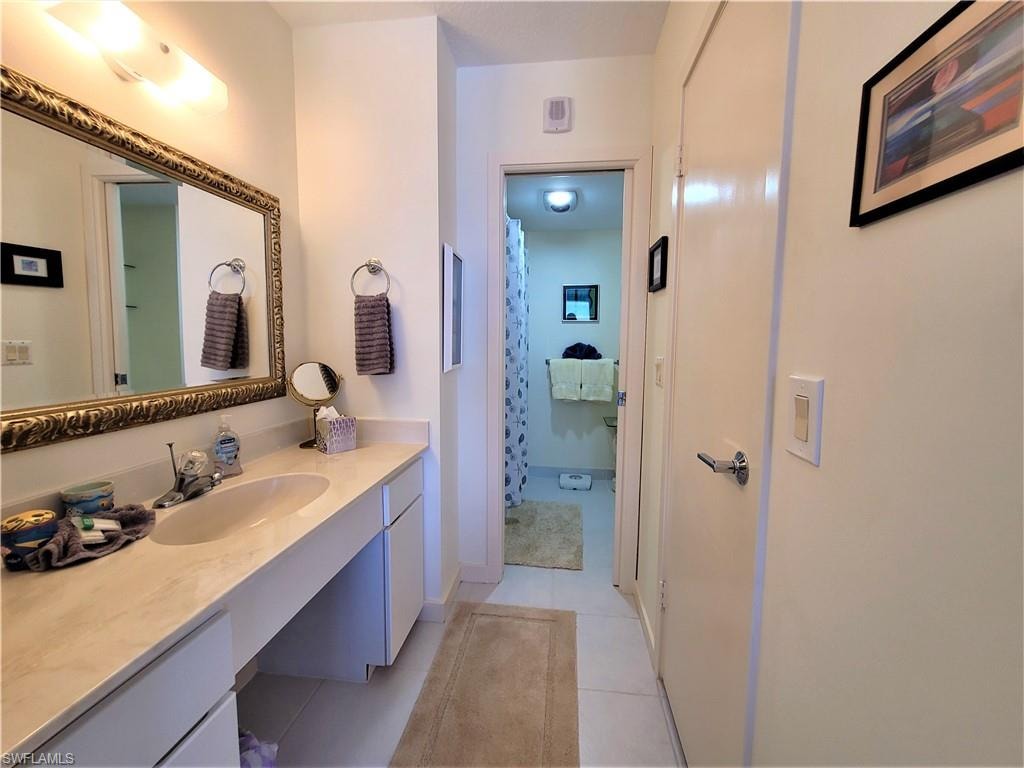 Bathroom featuring vanity, light tile patterned floors, and curtained shower