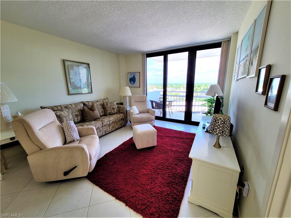 Living area with floor to ceiling windows, light tile patterned floors, and a textured ceiling