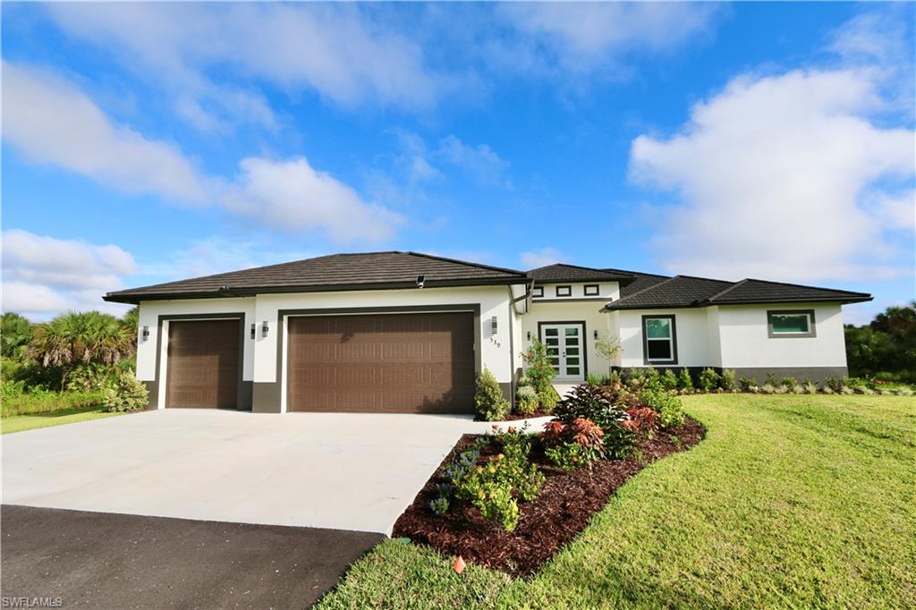 Prairie-style home with stucco siding, driveway, a garage, and a front yard