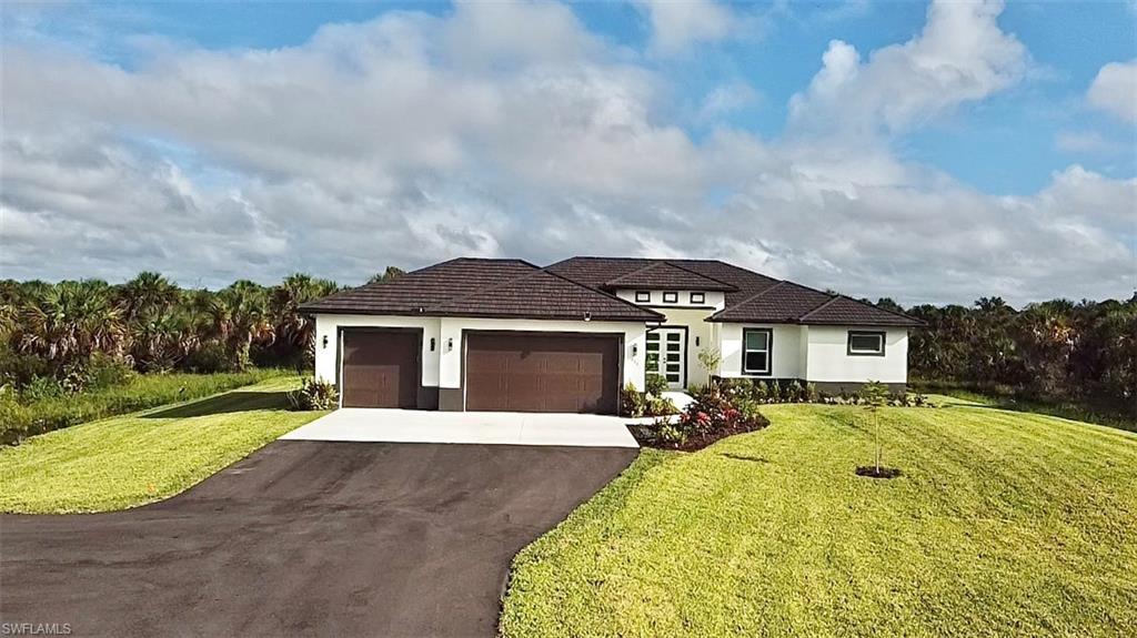 View of front of house featuring an attached garage, driveway, stucco siding, and a front lawn