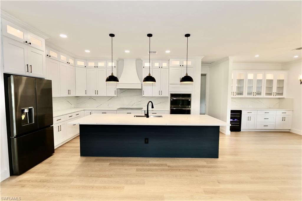 Kitchen featuring glass insert cabinets, black appliances, decorative backsplash, white cabinets, and recessed lighting