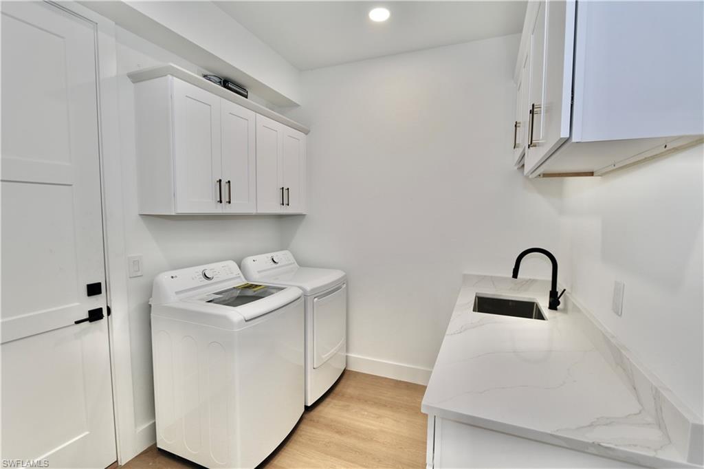 Laundry area with light wood-style floors, independent washer and dryer, cabinet space, and recessed lighting