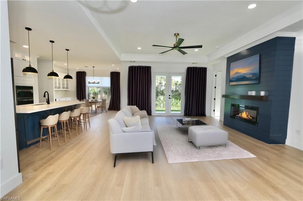 Virtually Staged Living room with a raised ceiling, plenty of natural light, light wood finished floors, a fireplace, and recessed lighting