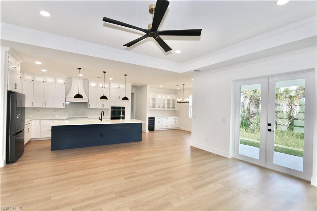 Unfurnished living room featuring a raised ceiling, a large fireplace, a chandelier, light wood finished floors, and recessed lighting