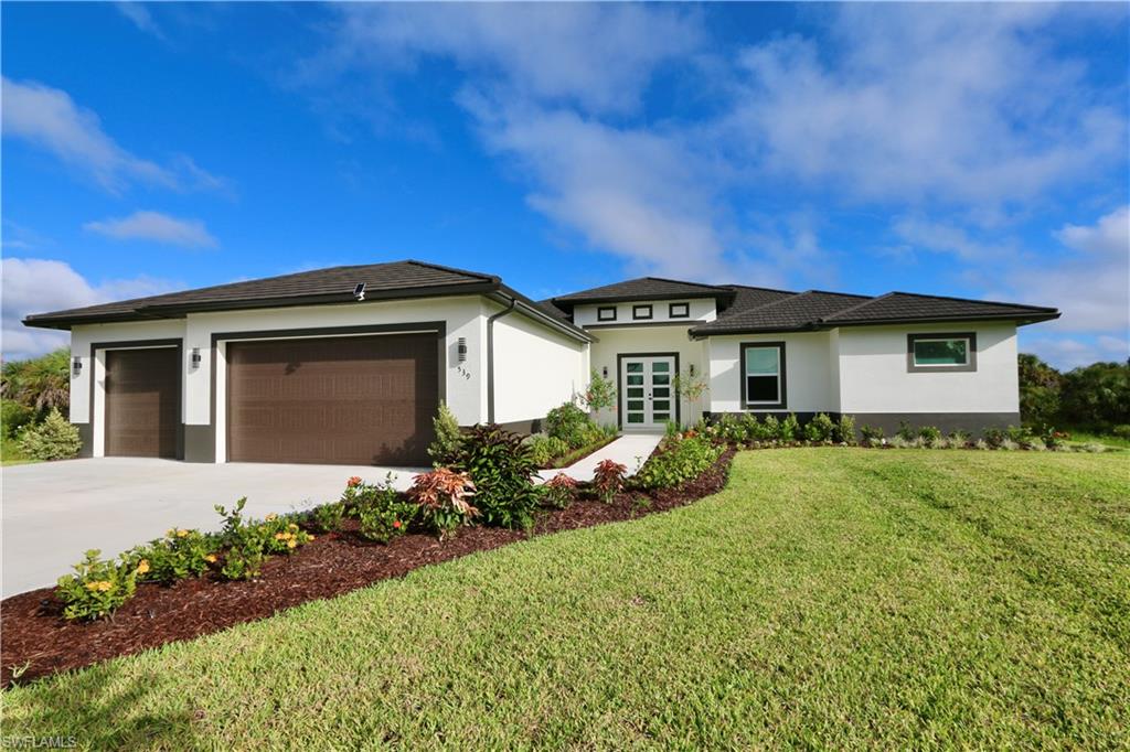 Prairie-style house with stucco siding, an attached garage, driveway, and a front lawn