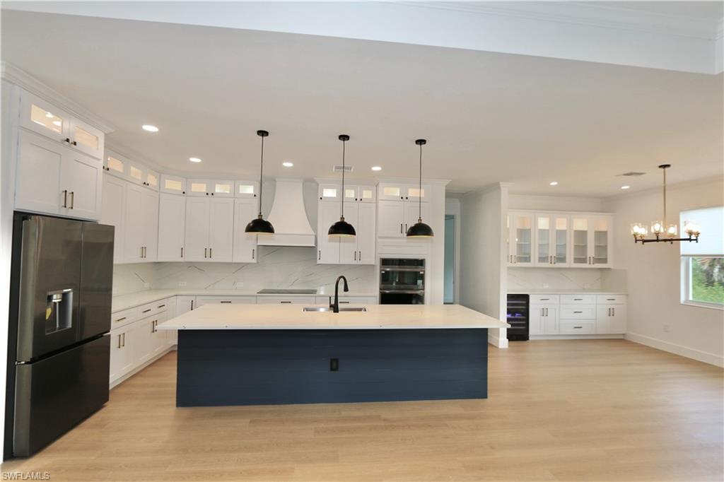 Kitchen with glass insert cabinets, black stainless steel appliances, white cabinets, decorative backsplash, and ornamental molding