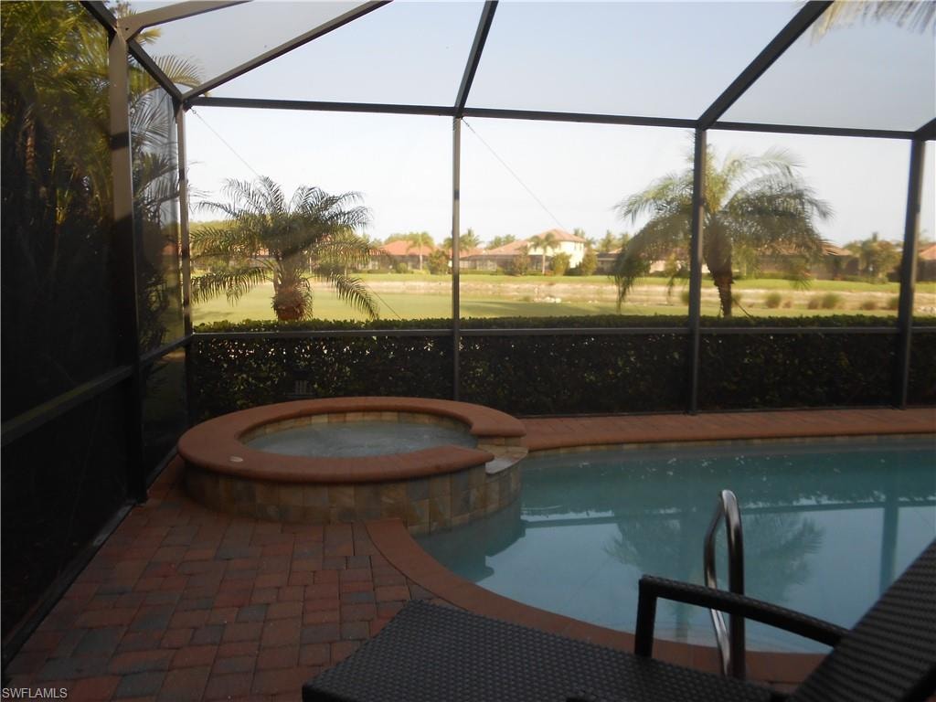 View of swimming pool featuring a sunroom, glass enclosure, and a pool with connected hot tub