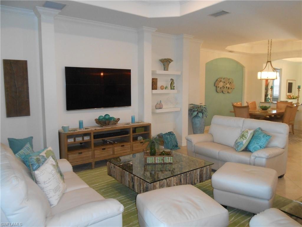 Tiled living area featuring a raised ceiling and ornamental molding