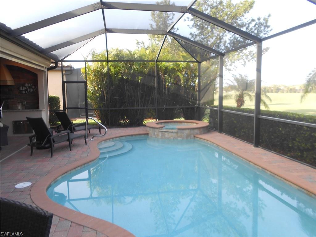 View of swimming pool featuring a lanai, a pool with connected hot tub, a sunroom, and a patio area