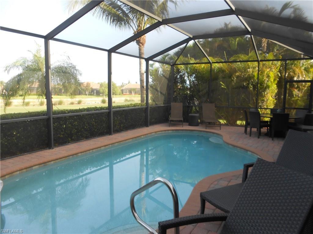 Outdoor pool with a sunroom, glass enclosure, and outdoor dining area