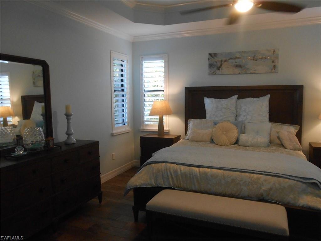 Bedroom with ornamental molding, dark wood-style flooring, and ceiling fan