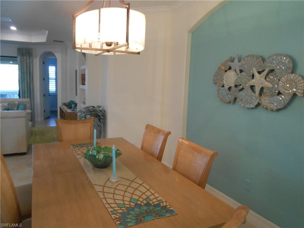 Dining room with a chandelier, arched walkways, and crown molding