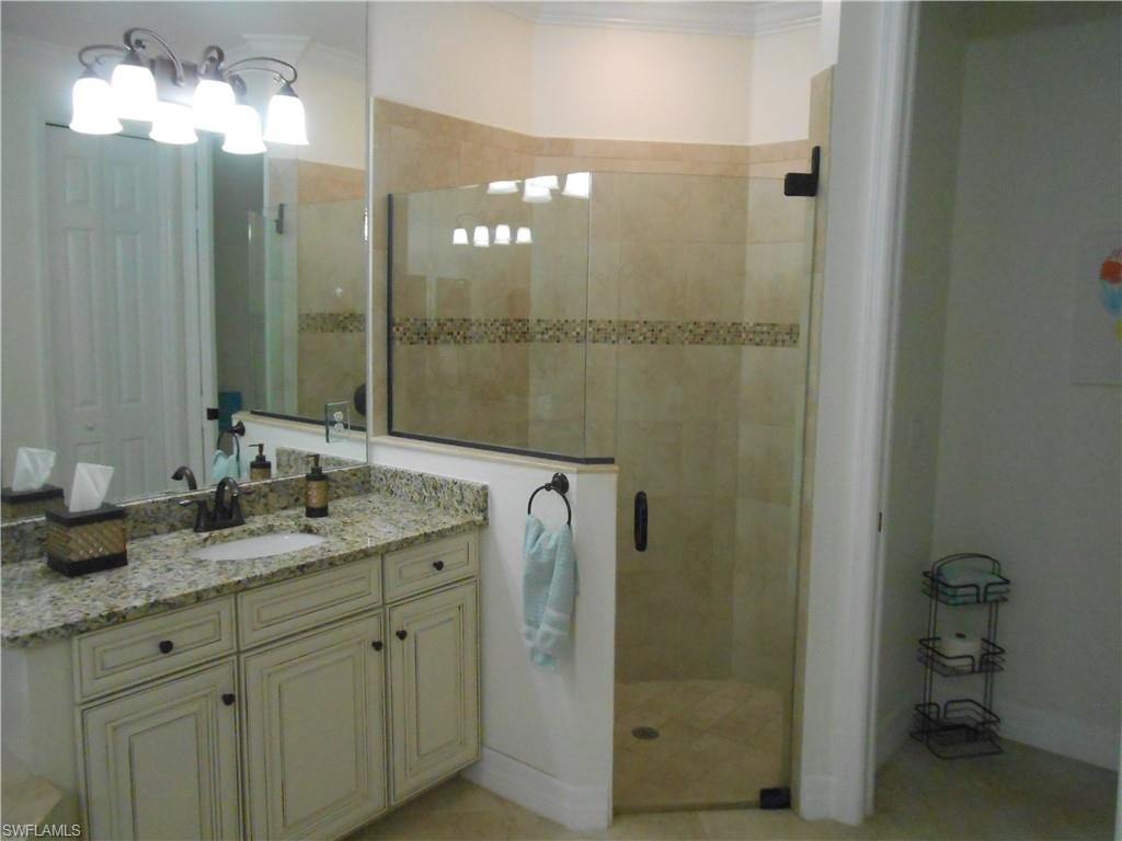 Bathroom featuring a stall shower, vanity, ornamental molding, and light tile patterned floors