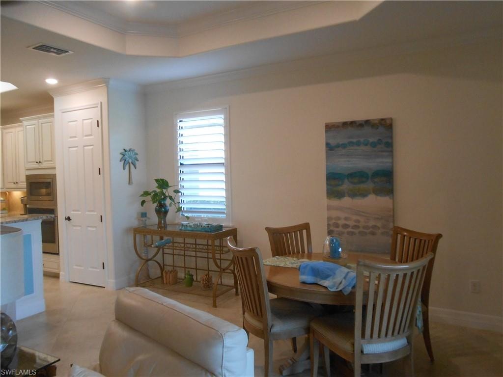 Dining space with ornamental molding, a tray ceiling, and recessed lighting