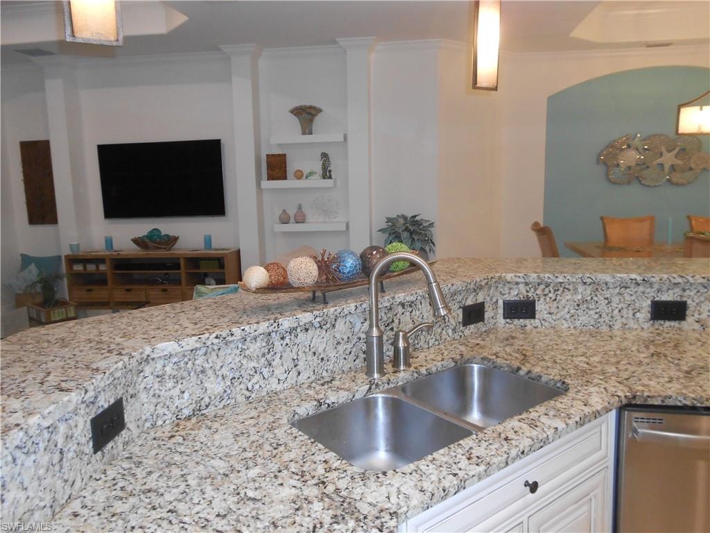 Kitchen featuring ornamental molding, light stone countertops, white cabinetry, and dishwasher