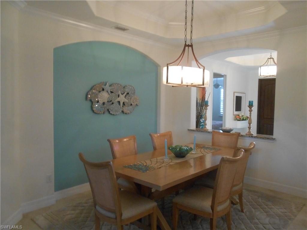 Dining area featuring a raised ceiling and crown molding