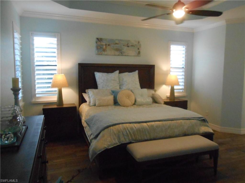 Bedroom featuring ornamental molding, dark wood-style floors, and a ceiling fan