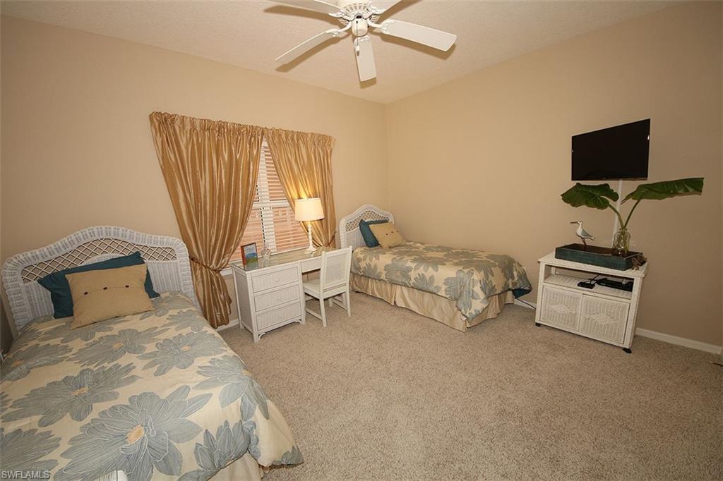 Carpeted bedroom with ceiling fan and baseboards