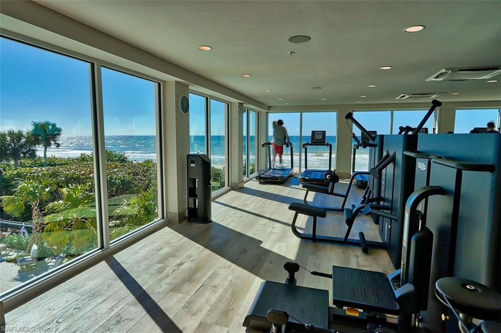Exercise room featuring a water view, light wood finished floors, and recessed lighting
