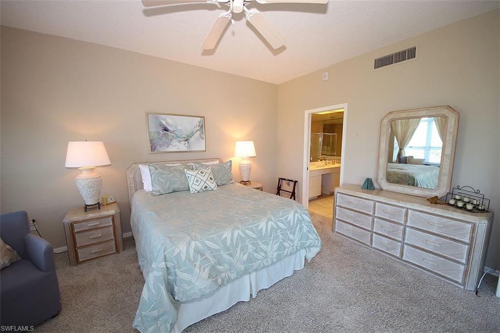 Bedroom featuring light carpet, ensuite bathroom, and ceiling fan