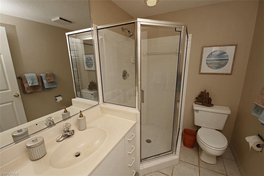 Bathroom with light tile patterned flooring, vanity, a shower stall, and a textured ceiling