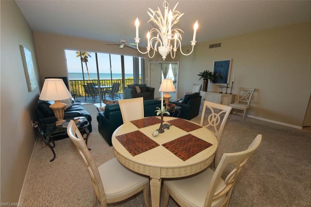 Carpeted dining space with a chandelier and a water view