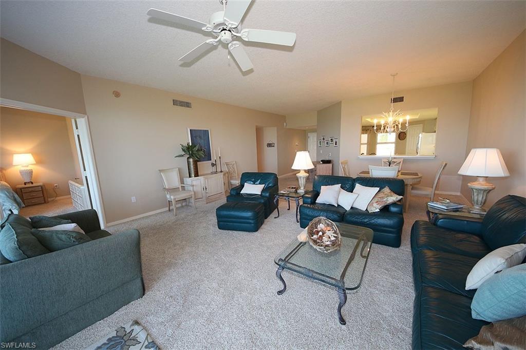 Living room with a chandelier, carpet flooring, and a ceiling fan