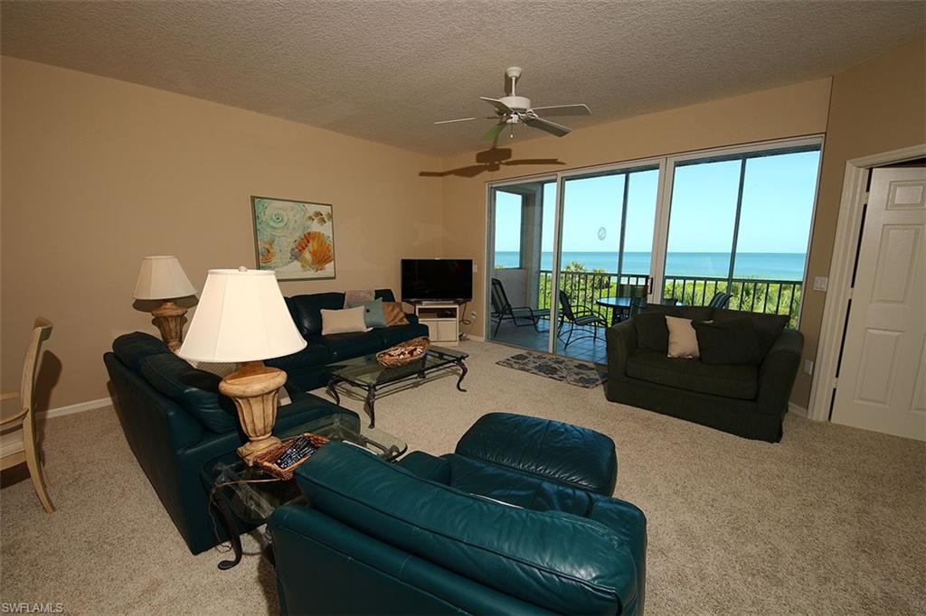 Carpeted living area with a textured ceiling and ceiling fan