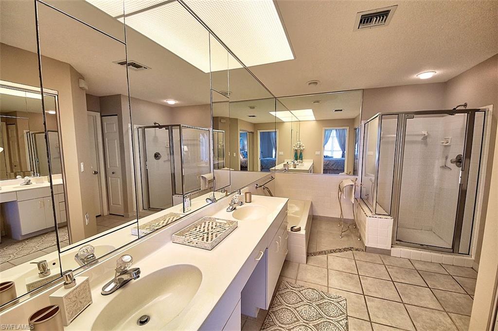 Bathroom with a shower stall, light tile patterned floors, a bath, double vanity, and a textured ceiling