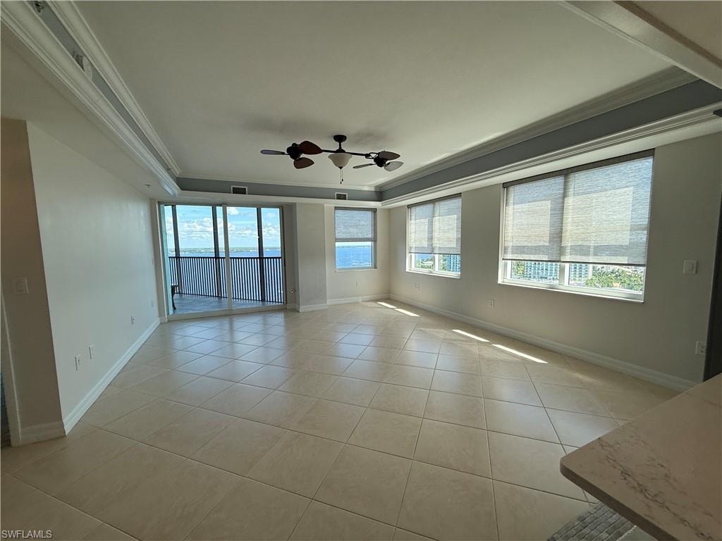 Living room with expansive views, coffered ceiling, light tile floors, crown molding, and a ceiling fan