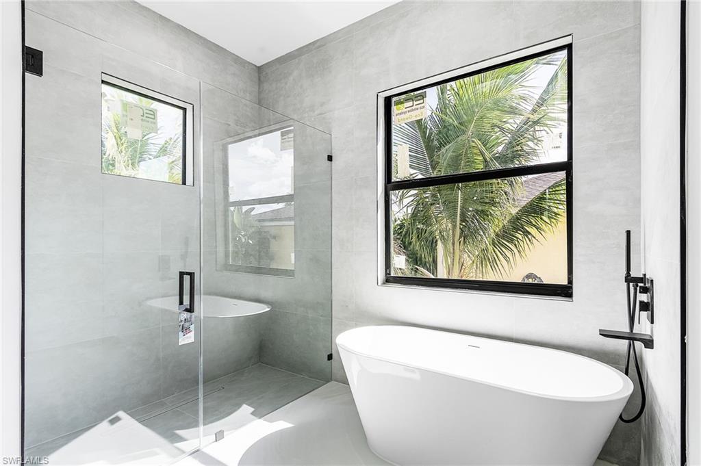 Full bath featuring a soaking tub, a stall shower, and tile walls
