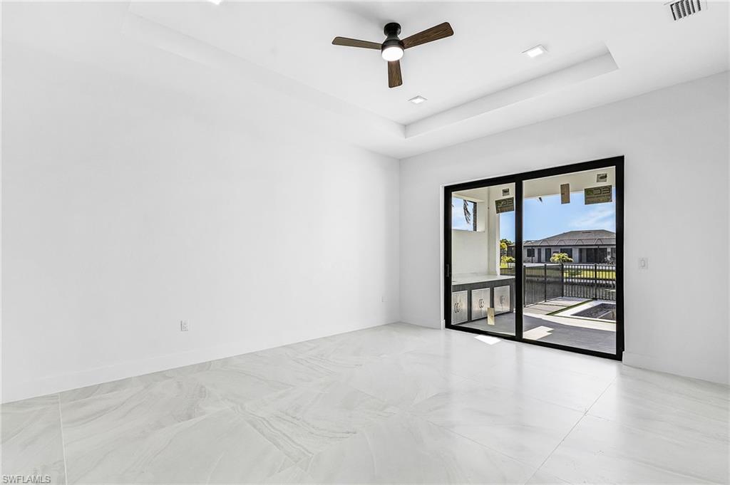 Empty room featuring a tray ceiling and ceiling fan