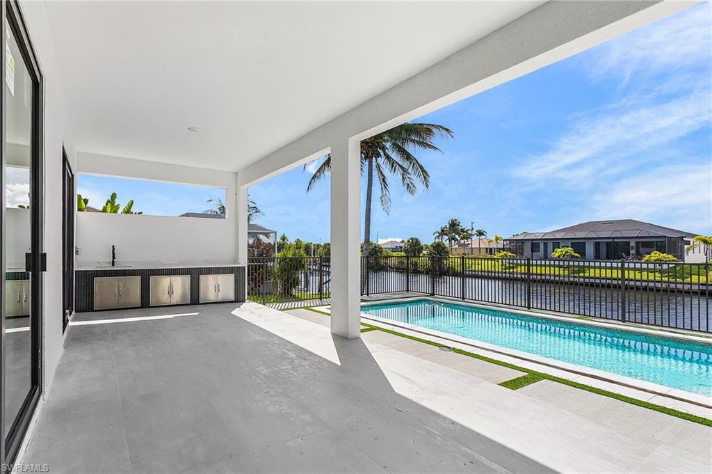 View of pool with a patio area, a water view, an outdoor kitchen, and a residential view