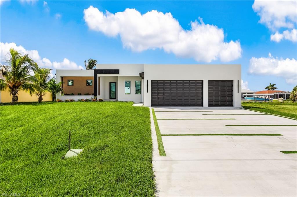 Contemporary home with a front lawn, driveway, stucco siding, and an attached garage