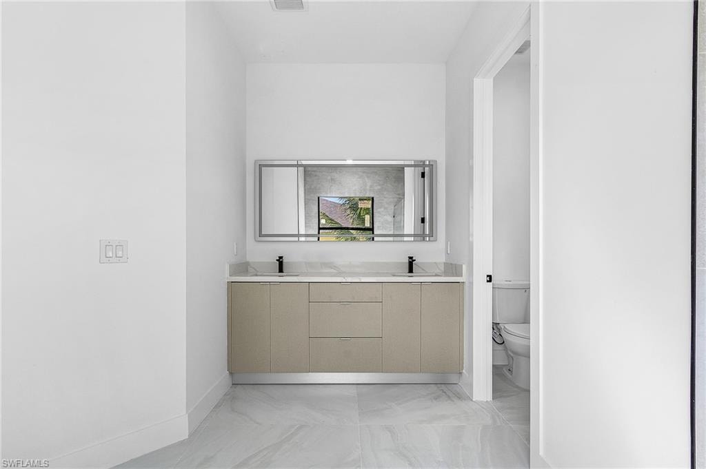 Full bathroom with toilet and double vanity