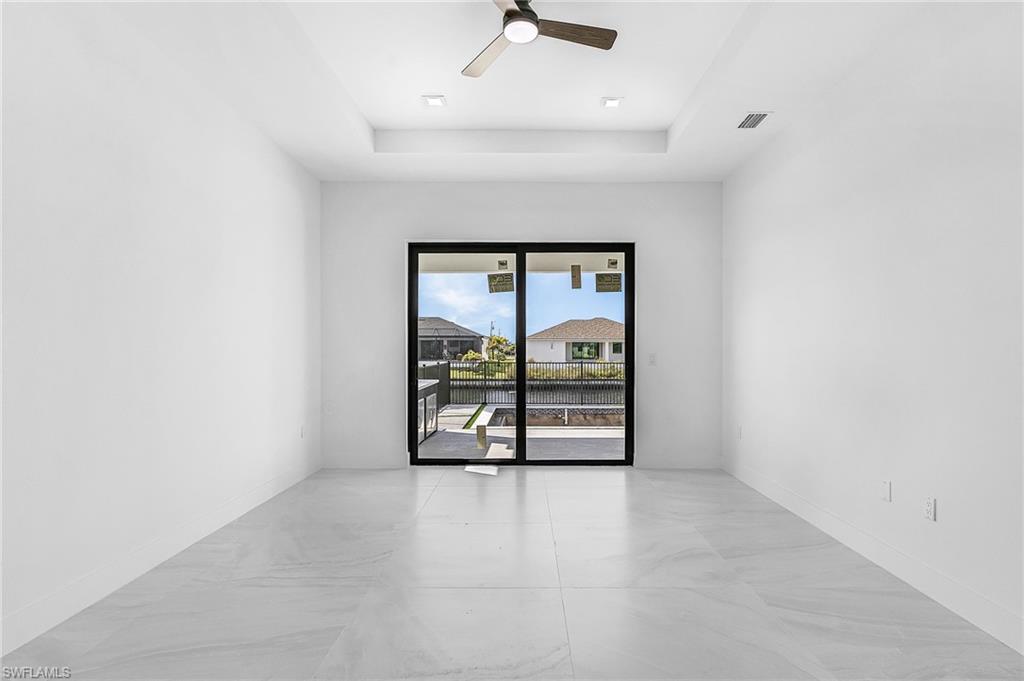 Unfurnished room featuring a raised ceiling and a ceiling fan