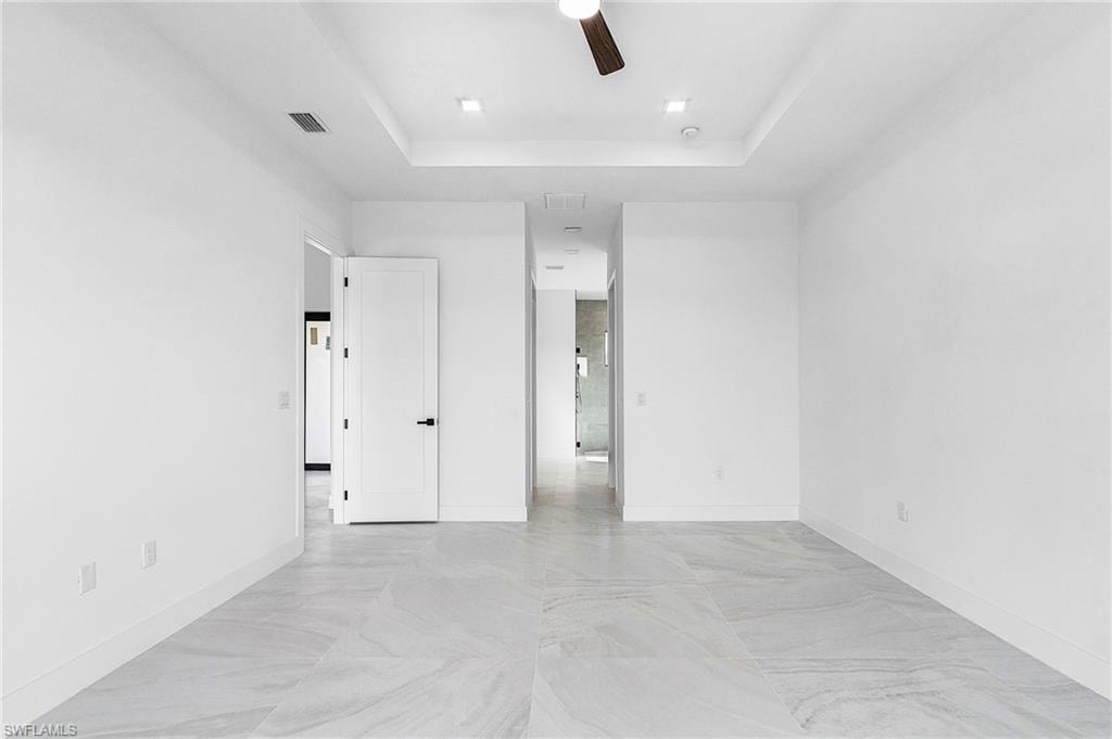 Spare room with a raised ceiling and a ceiling fan