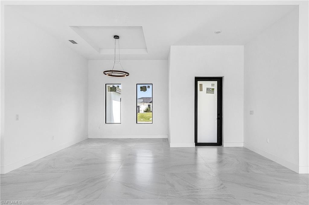 Unfurnished room featuring a raised ceiling and baseboards