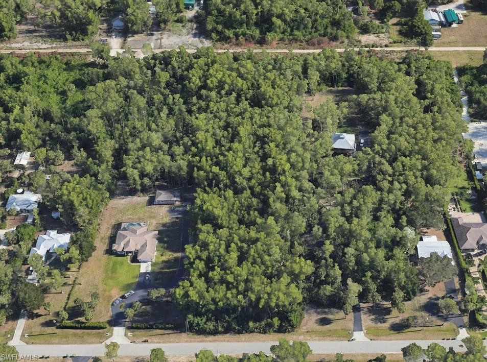 Aerial view of property and surrounding area with a heavily wooded area