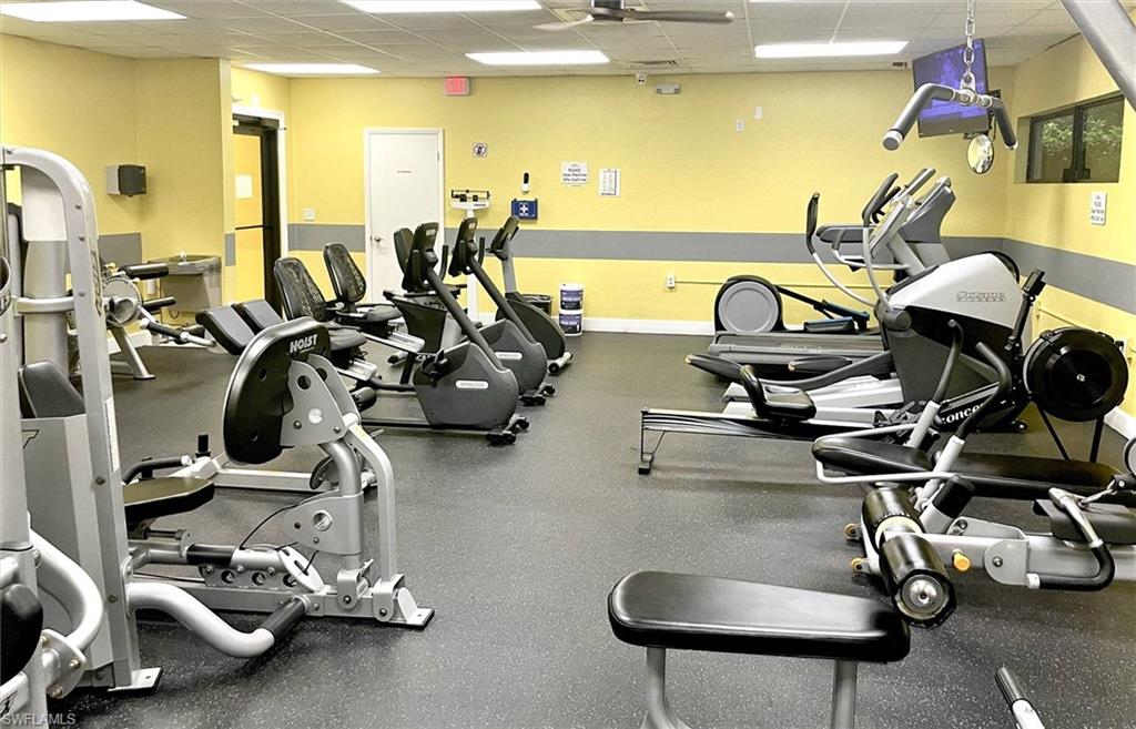 Fitness center featuring robust exercise equipment, durable rubber flooring, ceiling fan, and wall-mounted television