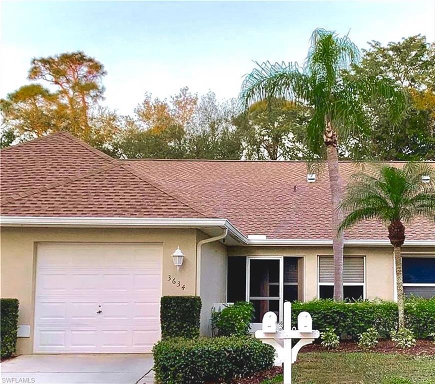 Single-story residence featuring a brown shingle roof, beige exterior siding, and a white paneled garage door
