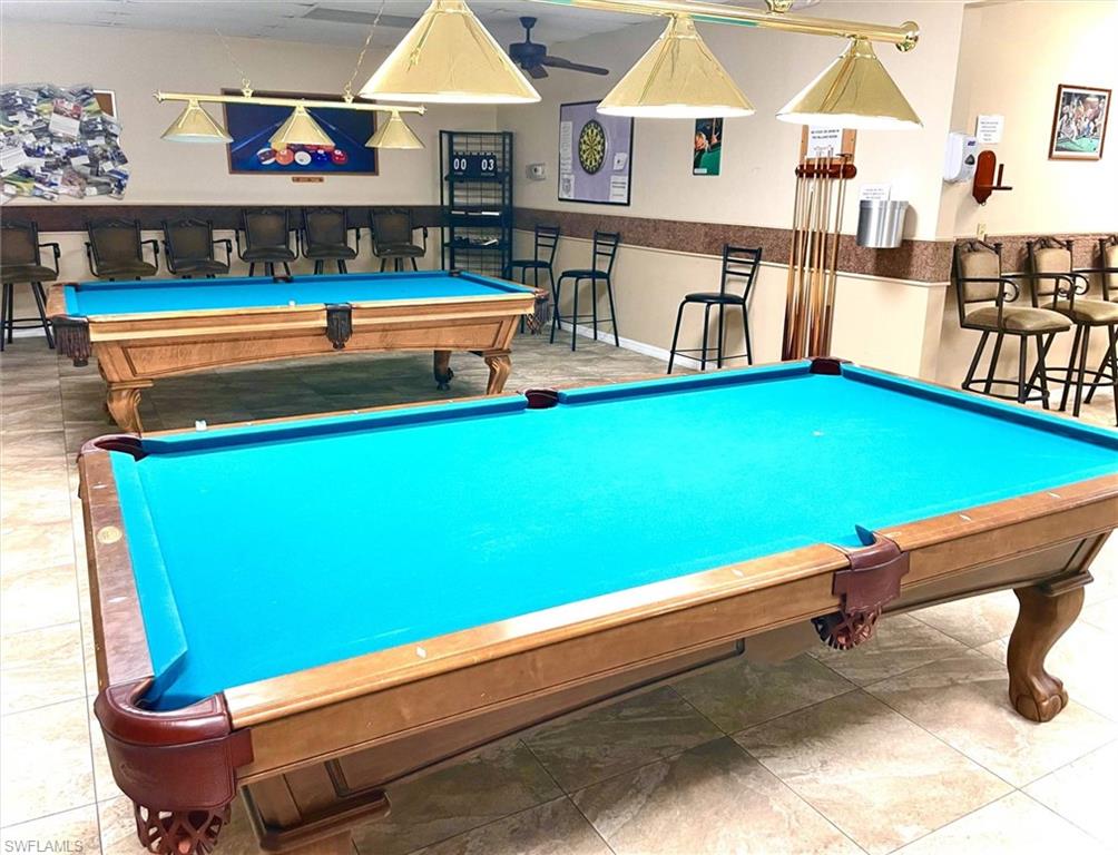 Recreation room featuring two billiards tables with teal felt, overhead task lighting, and tiled flooring