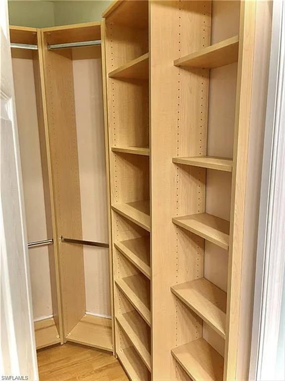 Custom closet system featuring light wood-finish shelving and chrome hanging rods