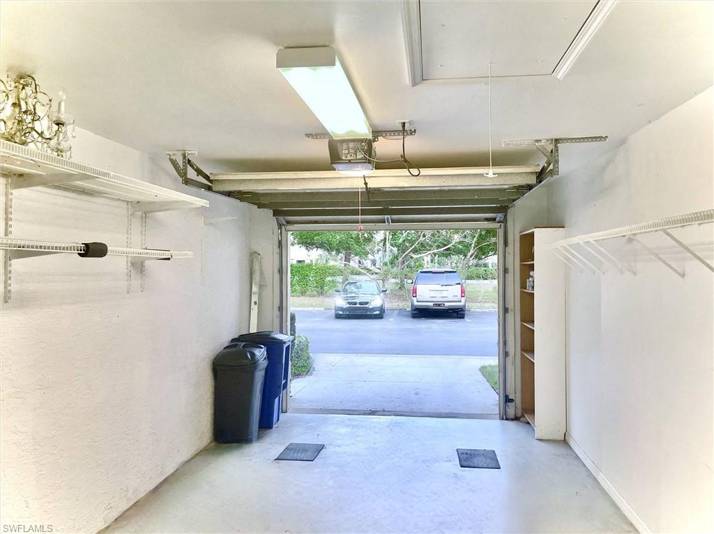 Integrated single-car garage featuring a concrete floor, overhead fluorescent lighting, a built-in shelving system, and a built-in storage unit