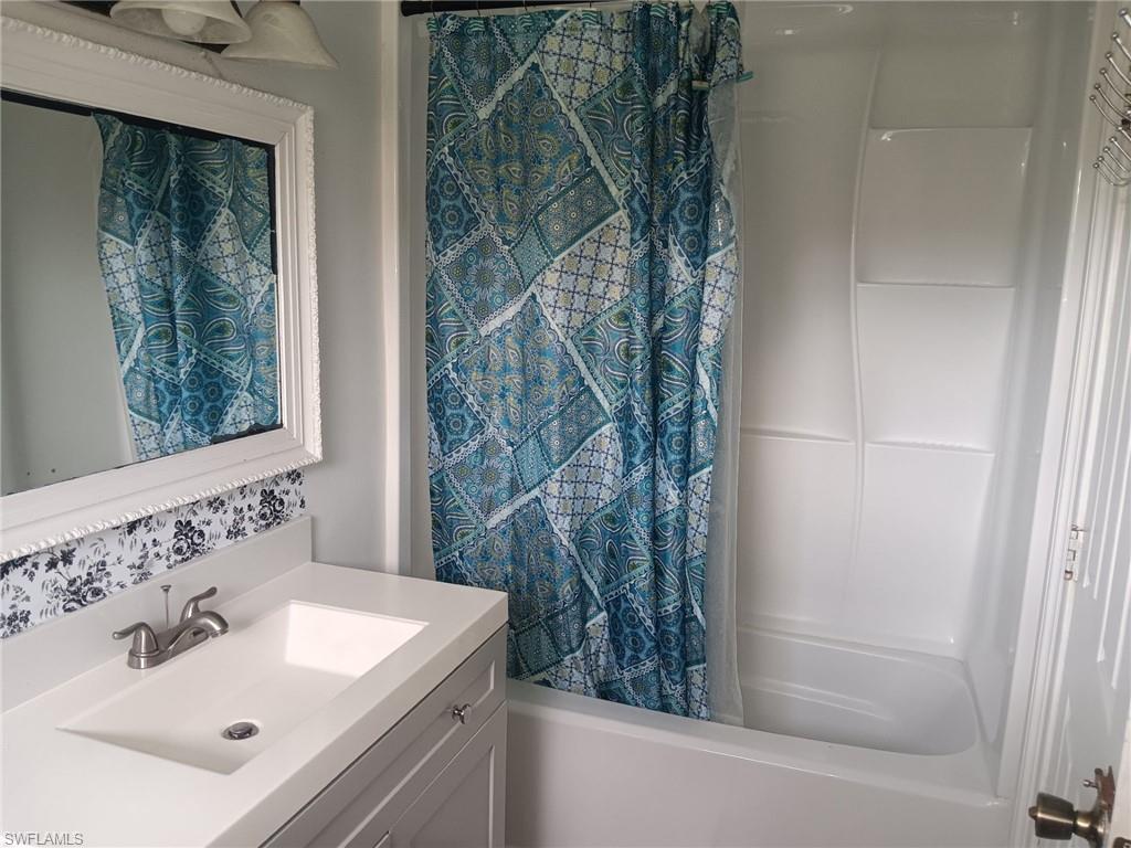 Bathroom featuring shower / bath combination with curtain and vanity