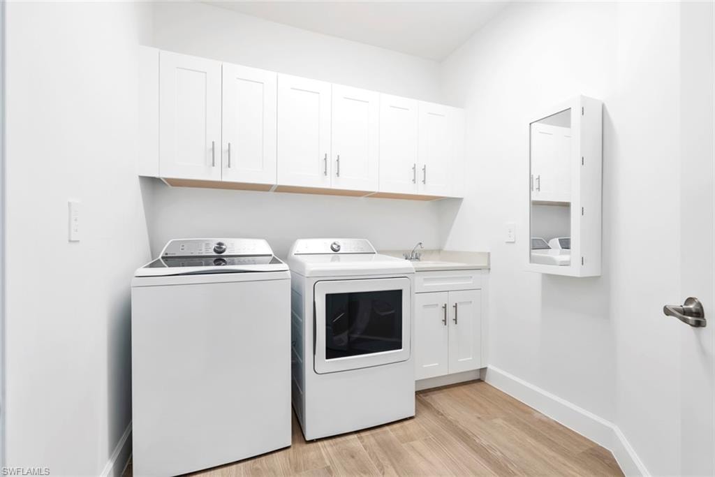 Washroom with separate washer and dryer, light hardwood / wood-style floors, cabinets, and sink