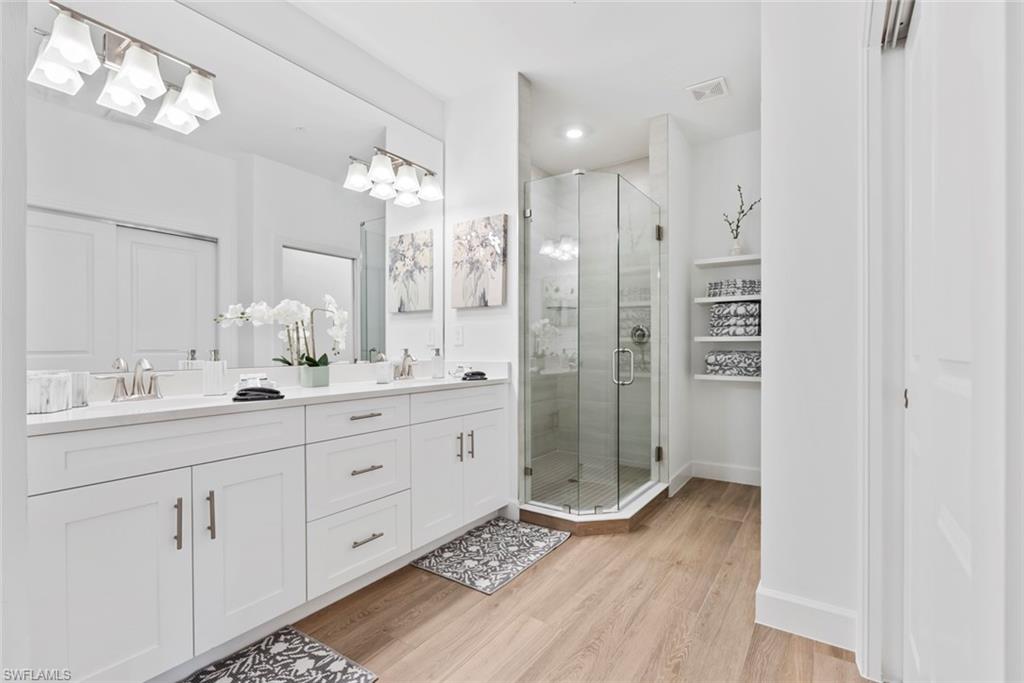 Bathroom with hardwood / wood-style floors, vanity, and a shower with shower door
