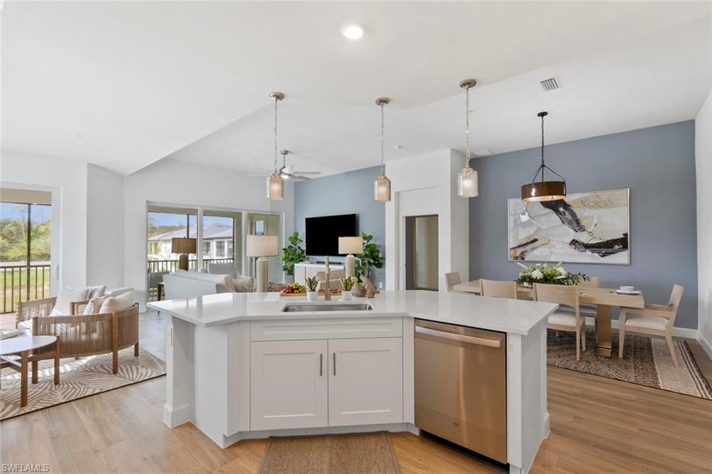 Kitchen featuring light wood-type flooring, white cabinets, sink, decorative light fixtures, and dishwasher