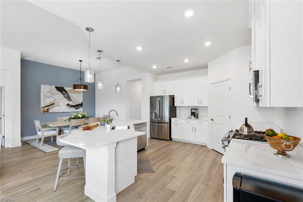 Kitchen featuring white cabinets, sink, an island with sink, and appliances with stainless steel finishes