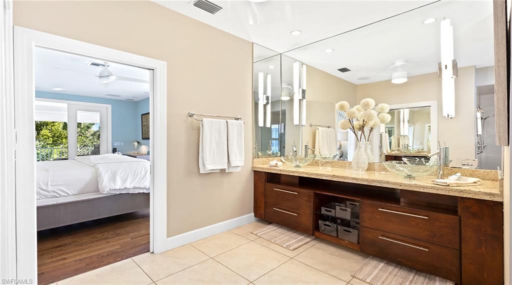 Ensuite bathroom featuring double vanity, light tile patterned floors, and recessed lighting